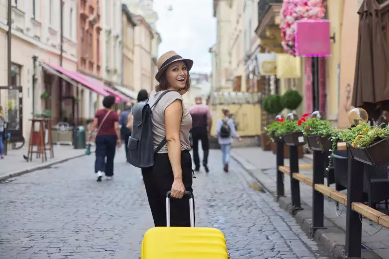 Smiling woman traveling in tourist city with suitcase