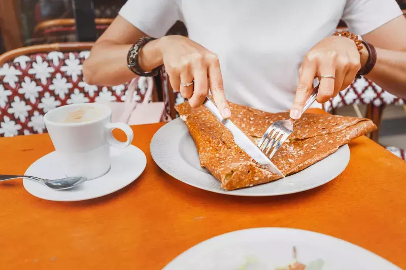 Woman eating traditional french crepes galette - baked pancakes with cheese filling