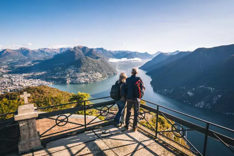 Mature couple hike above lake Lugano in the morning