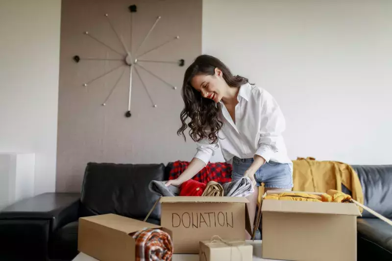 Woman holding Clothes with Donate Box In her room, Donation Concept