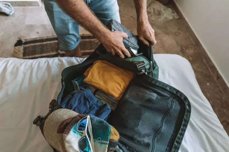 Top view of male traveler packing for a trip, puts clothes in a duffel bag