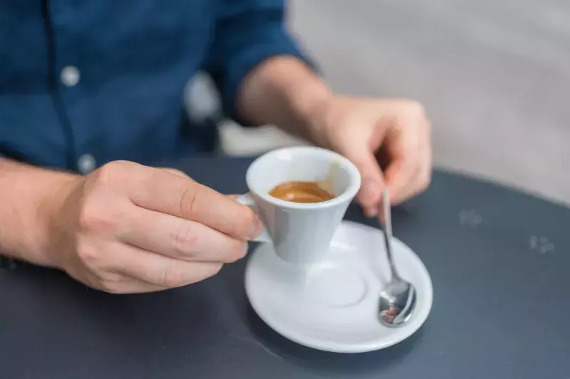 man enjoys an espresso at an outdoor cafe