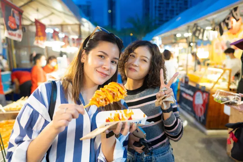 two women enjoying in street food.