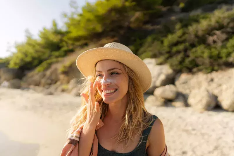 Young woman applying sunscreen at the beach