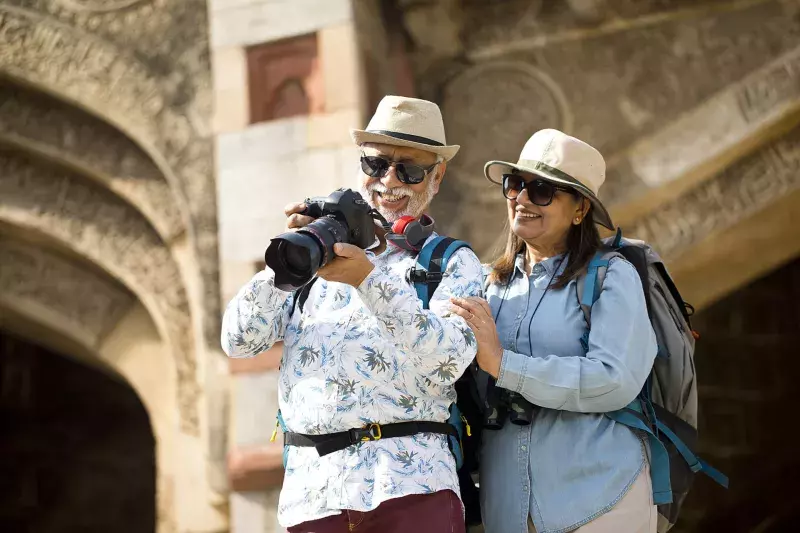 couple watching photos from travel on digital camera during vacation after retirement