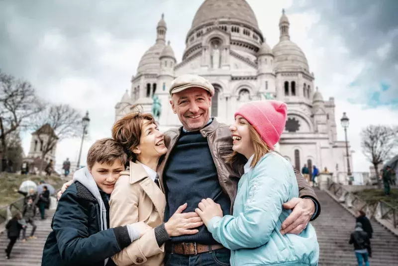 happy french family embraced in front of Sacre Coeur in Paris